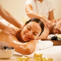Young couple enjoying in back massage at health spa. Focus is on smiling woman.